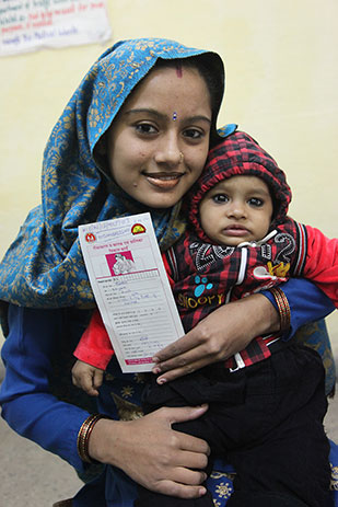 A happy mother shows her child's vaccination card in New Delhi, India.